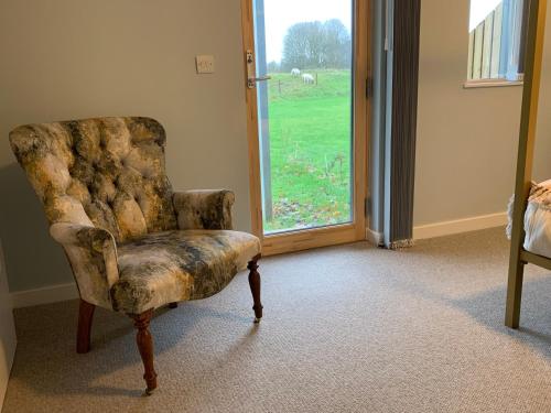 an old chair sitting in a room with a window at 3 Beechwood at Thoulstone Park in Westbury