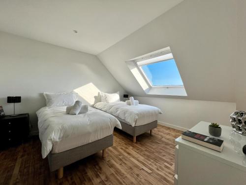 Un dormitorio abuhardillado con dos camas y una ventana. en Villa Cotton-vue mer et jacuzzi-6ch, en Plobannalec-Lesconil