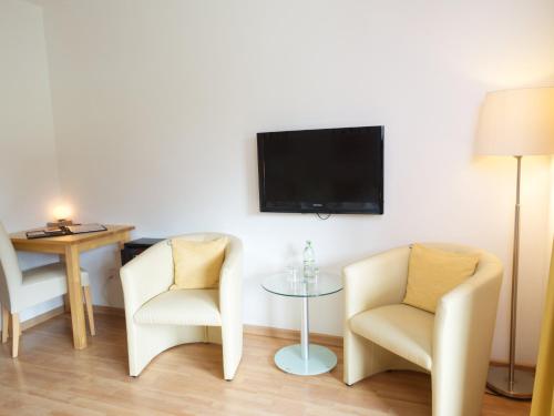 a living room with two chairs and a table and a tv at Hotel Garni Landhaus Sonnenstern in Schönau am Königssee