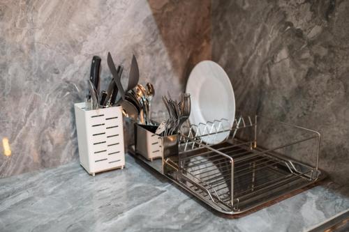 a counter with a plate and a basket of utensils at A Stylish Stay in Batangas City - Unit 103 in Batangas City