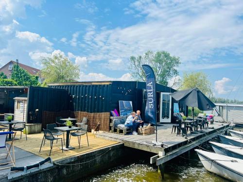 a couple sitting on a dock next to a boat at Heerlijke Houseboat "Tulip" in Monnickendam dichtbij Amsterdam in Monnickendam