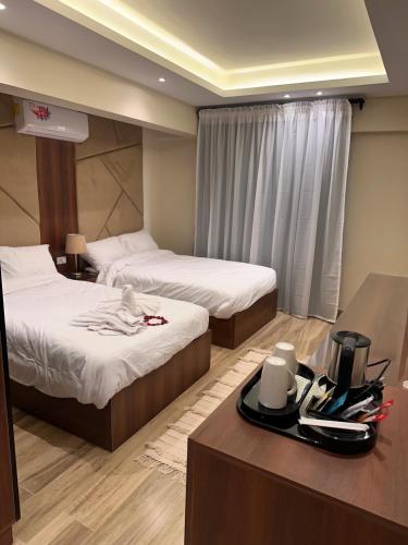 a hotel room with two beds and a table with a tray at Giza Palace Pyramids View in Cairo
