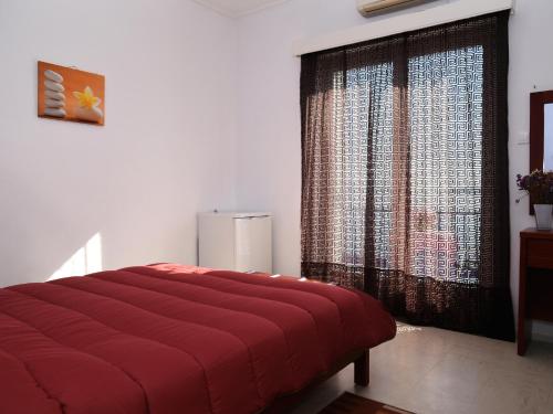 a bedroom with a red bed and a large window at Hotel Solon in Tolo