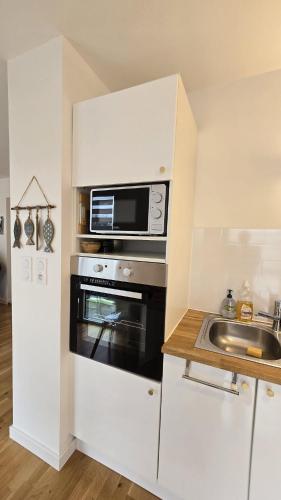 une cuisine avec un micro-ondes et un évier dans l'établissement Vacances Ô Kastel - Studio Centre Ville proche de la mer, à Fouesnant