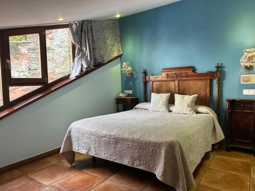 Un dormitorio con una cama con paredes azules y una ventana en La Casona de Pío, en Cudillero
