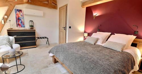 une chambre avec un grand lit avec un mur rouge dans l'établissement Le Mas Saint Martin, à Vallon-Pont-dʼArc