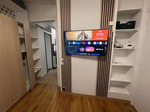 Un televisor de pantalla plana colgado en la pared de una habitación. en APPARTEMENT AU CŒUR DE MARAIS DANS CENTRE de PARIS, en París