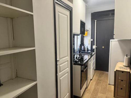 cocina pequeña con puerta blanca y nevera en APPARTEMENT AU CŒUR DE MARAIS DANS CENTRE de PARIS, en París