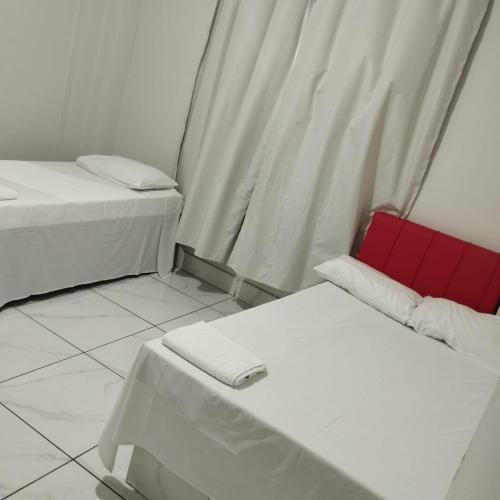 a room with two beds and a red chair at Hotel Rodoviária Belo Horizonte in Belo Horizonte