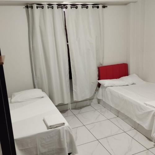 a room with two beds and a window with curtains at Hotel Rodoviária Belo Horizonte in Belo Horizonte