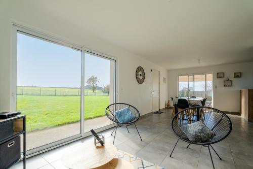 un salon avec deux chaises et une grande fenêtre dans l'établissement Gite Les Portes De Montafilan, à Corseul