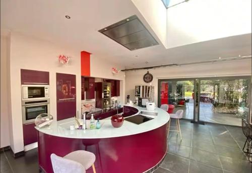 une cuisine avec un comptoir blanc et des placards violets dans l'établissement Villa Contemporaine Piscine Jacuzzi, à Villebret