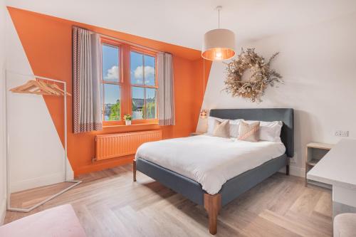 a bedroom with a bed with an orange wall at Esperance - Brand New luxury studio with parking in Bowness-on-Windermere