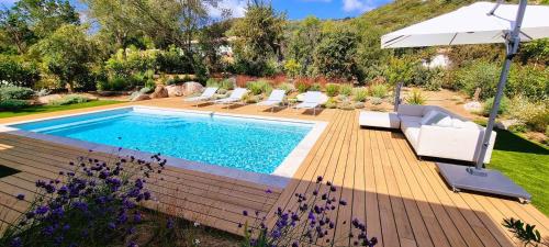 - une piscine avec des chaises et un parasol dans la cour dans l'établissement Villa Alba, 8 pers, piscine chauffée, 5 minutes plage, à Cirendinu