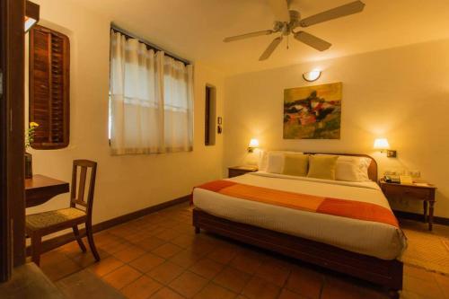 a bedroom with a bed and a desk with a fan at Coconut Lagoon Kumarakom - A CGH Earth Experience in Kumarakom