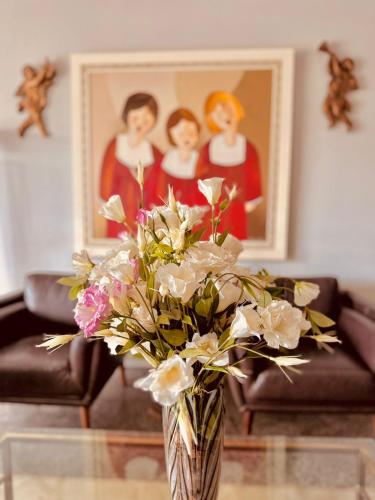 a vase with flowers on a table in a living room at Skalla Hotel Nova Odessa in Nova Odessa