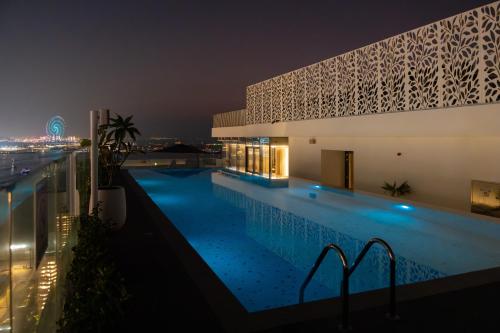 a swimming pool in front of a building at night at Tumbi Hotel Dubai The Palm,Tapestry Collection Hilton in Dubai