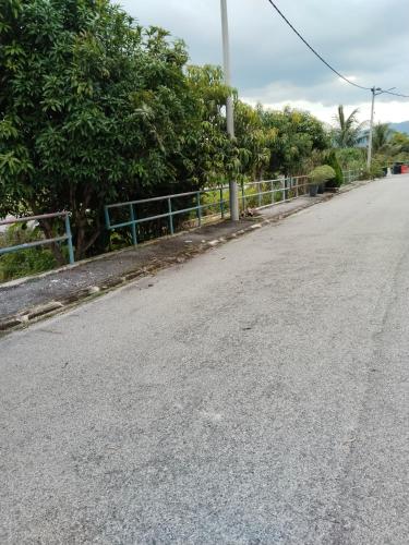 an empty street with a fence and trees at Homestay Lyn Impian in Tanjung Rambutan