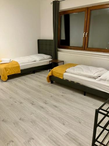 two beds in a room with wooden floors at Helle 4 Zimmer, Küche, Bad, WLAN, 24-7, Parkplatz, 4-10 Personen in Landshut