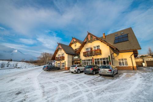 a house with cars parked in the snow at Penzión Lomnicky in Stará Lesná