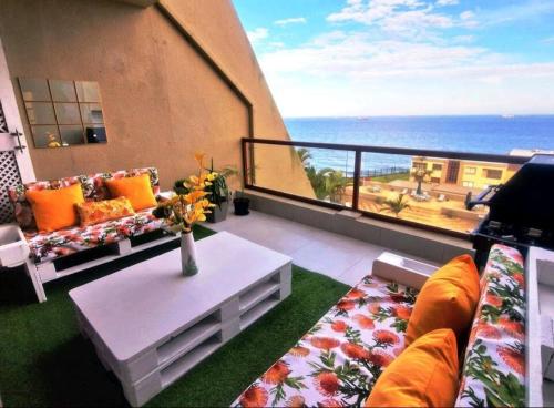 a living room with a balcony with a view of the ocean at Ripple In Time -BBQ - Aircons- 4 Adults 2 kids in Umdloti