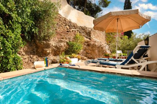 a swimming pool with two chairs and an umbrella at La Cuadra in Frigiliana