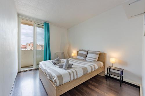 a bedroom with a bed and a large window at Le Pierre Cazeneuve vue et climatisation in Toulouse