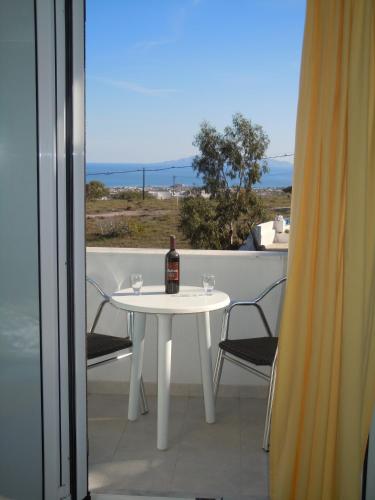 a bottle of wine sitting on a white table on a balcony at Atlas Pension in Karterados