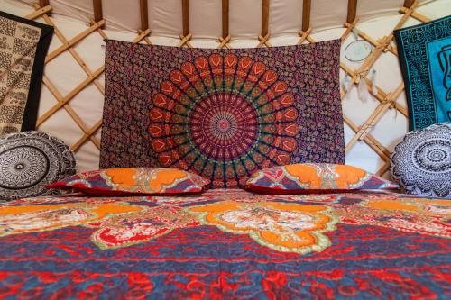 a bed with pillows on it with a colorful rug at Agricampeggio Equinox in Carpignano Sesia
