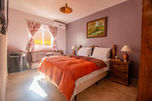 a bedroom with a large bed with an orange blanket at Nona Amabile in São Lourenço do Sul
