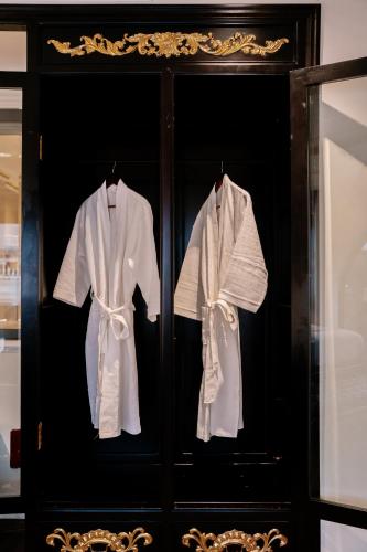 two white shirts are hanging in a cabinet at Bao An Hotel Hung Yen in HÆ°ng YÃªn