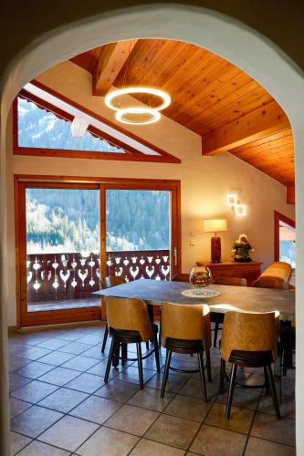 une salle à manger avec une table et des chaises et une grande fenêtre dans l'établissement Chalet Les Barmés, à Champagny-en-Vanoise