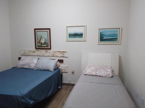 een slaapkamer met twee bedden en drie foto's aan de muur bij Cobertura com churrasqueira São Vicente in São Vicente