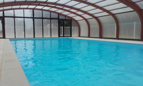 - une grande piscine dans un bâtiment doté de fenêtres dans l'établissement Chalet de la Butte aux Cerfs, à Saint-Manvieu-Bocage