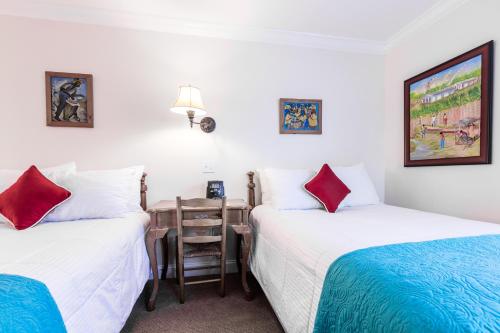 two beds in a room with a table and a desk at The Caribbean Court Boutique Hotel in Vero Beach