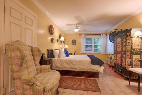 a bedroom with a bed and a chair at The Caribbean Court Boutique Hotel in Vero Beach