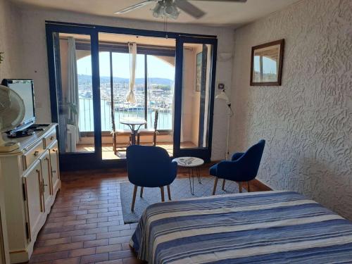 - une chambre avec un lit, des chaises et un balcon dans l'établissement Le Coin Bleu - Studio vue mer et port à 2 pas de la plage aux Marines de Cogolin pour 2 personnes, à Cogolin