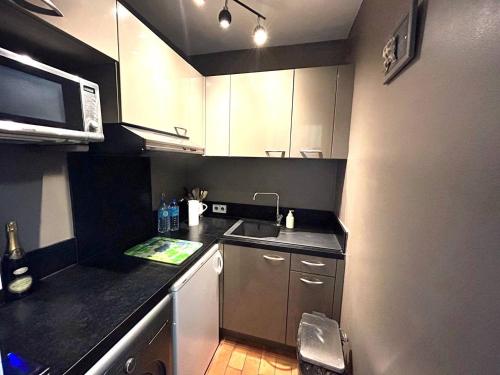 une petite cuisine avec un évier et un micro-ondes dans l'établissement Le Coin Bleu - Studio vue mer et port à 2 pas de la plage aux Marines de Cogolin pour 2 personnes, à Cogolin