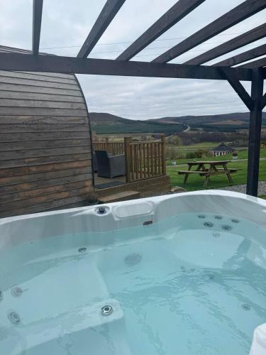 a hot tub under a roof with a picnic table at Daviot Luxury Pods in Inverness