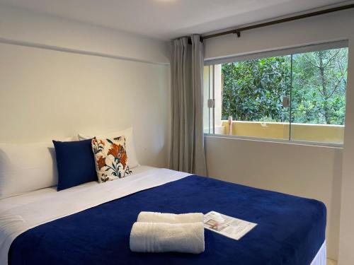 a bedroom with a blue and white bed with a window at Mar a Vista Suítes ILHABELA in Ilhabela