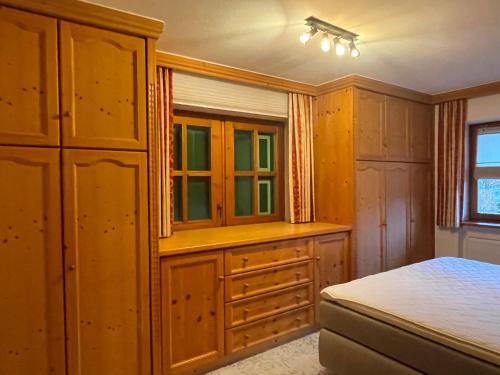 a bedroom with a bed and wooden cabinets and a window at Landhaus Franziskus in Reit im Winkl