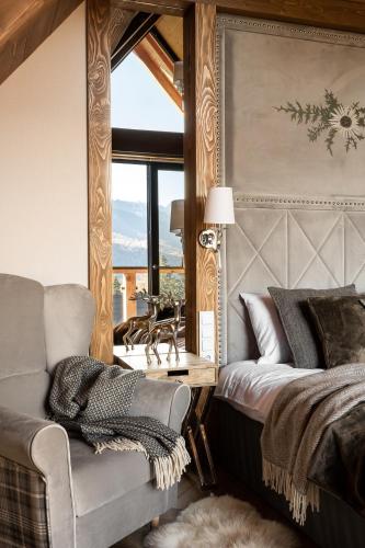 a bedroom with a bed and a chair and a window at Villa La Roca Garden and Spa in Kościelisko