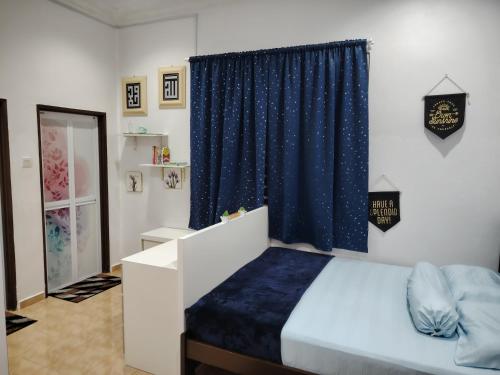una camera da letto con un letto e una tenda blu di Sri MaLati Homestay and Event Space a Balik Pulau