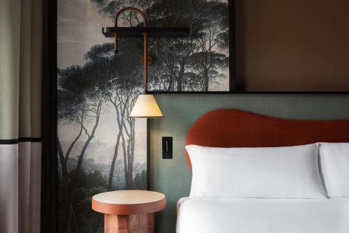 a bedroom with a bed and a table and a painting at The Spring House Hotel Rome Vatican, Tapestry Collection Hilton in Rome
