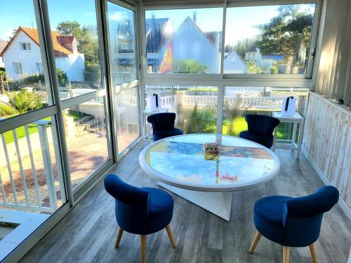 une pièce avec une table, des chaises et des fenêtres dans l'établissement Charmante villa de bord de mer, à Pirou