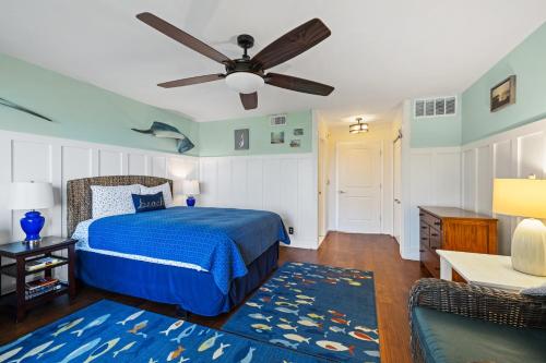 a bedroom with a blue bed and a ceiling fan at Whitman by the C townhouse in Cedar Key