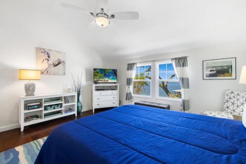 a bedroom with a blue bed and a window at Whitman by the C townhouse in Cedar Key