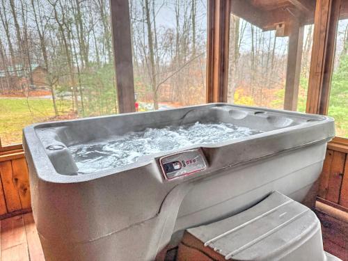 a bath tub filled with water next to a window at Ferngully Creek Cabins in Millersburg