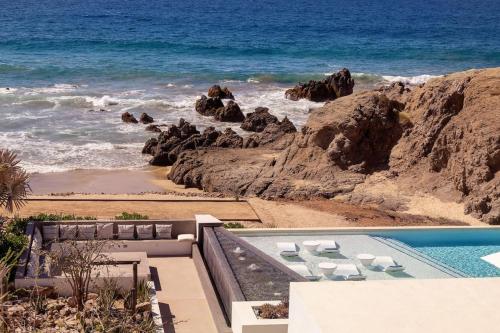 a house with a swimming pool next to the ocean at Stylish Oceanfront Condo with Panoramic Views in El Pescadero