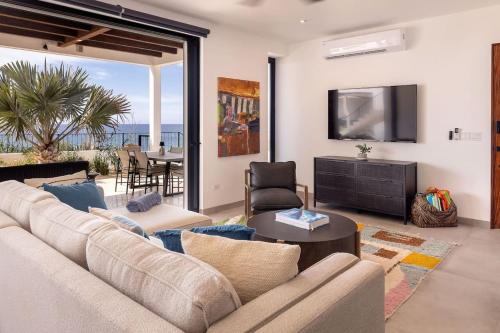 a living room with a couch and a tv and a table at Boutique Ocean Escape with Relaxing Amenities in El Pescadero